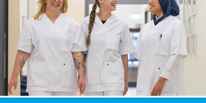 Drei Pflegeschülerinnen gehen gemeinsam über einen Gang.