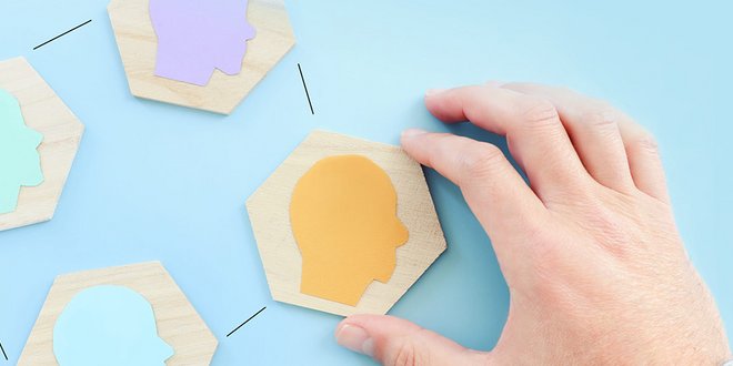 Hand puzzelt Holzteile mit Kopfsilhouetten