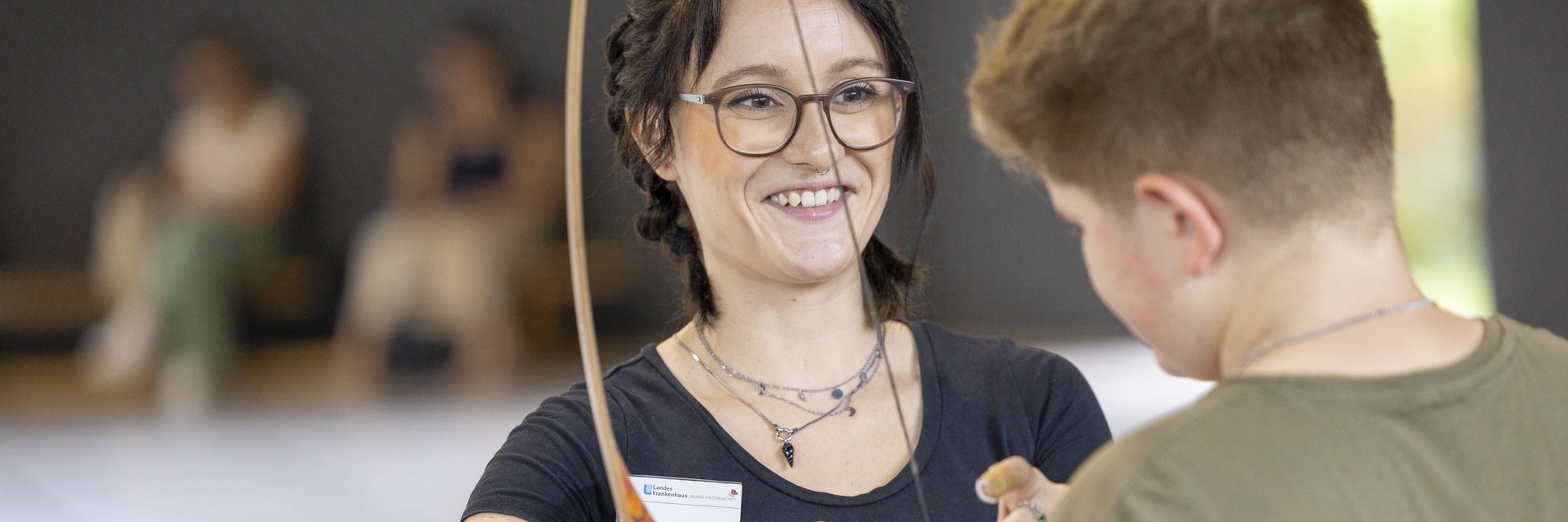 Pflegefachkraft mit Jugendlichem beim Bogenschießen